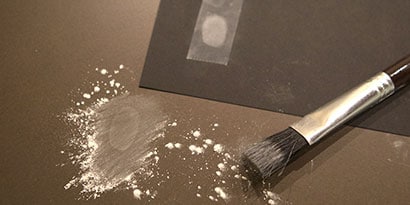 Use a small brush and gently brush away the powder